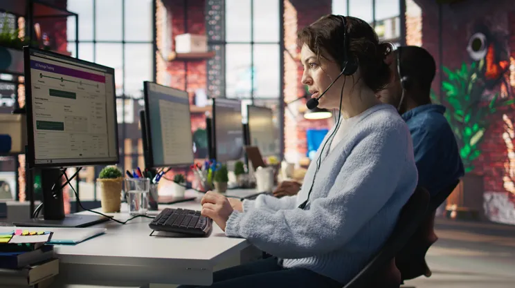 Customer service representative wearing a headset at a computer